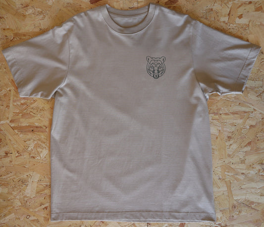 Beige t-shirt with a bear logo on a wooden surface