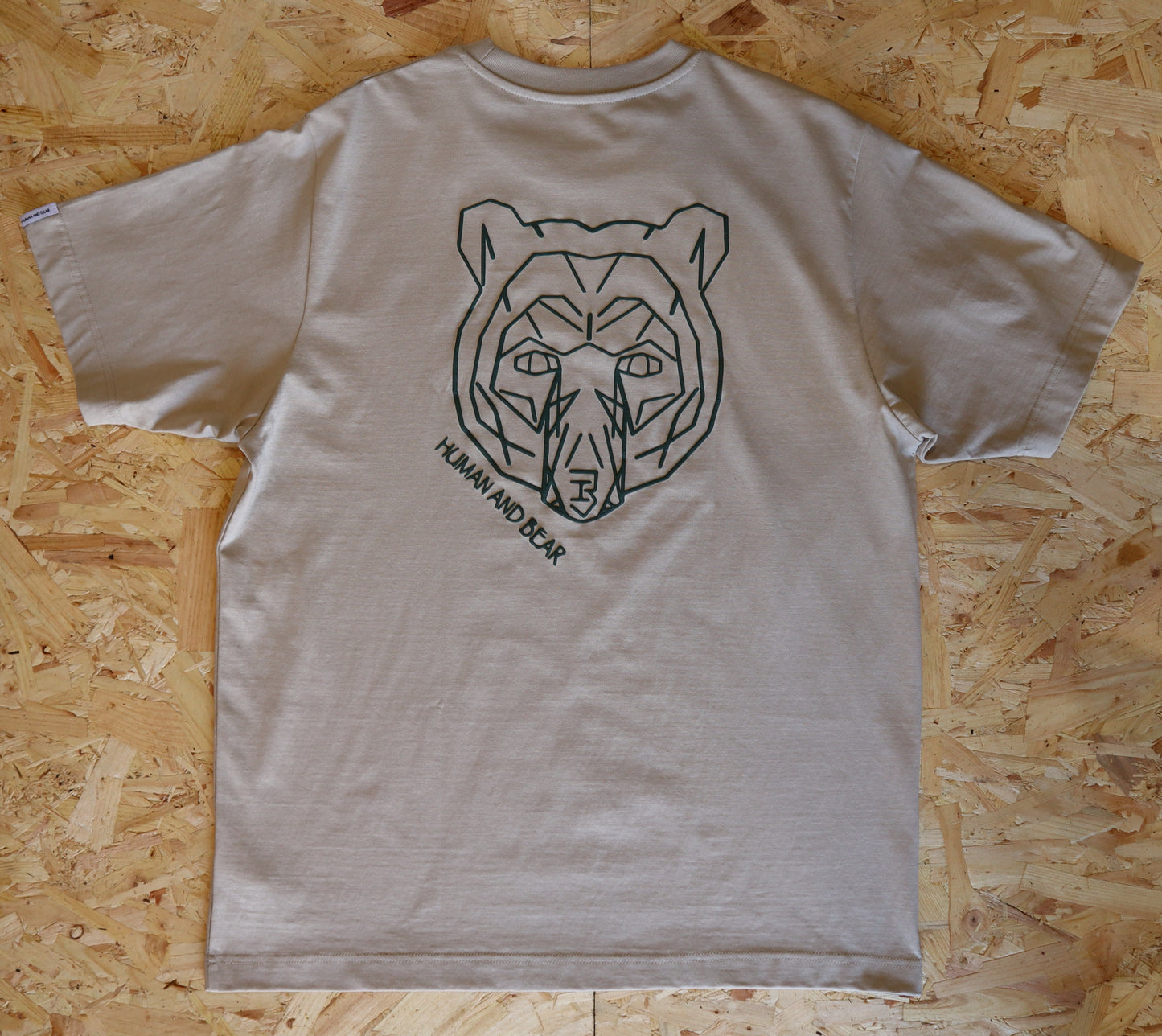 Beige t-shirt with bear graphic on a wooden surface