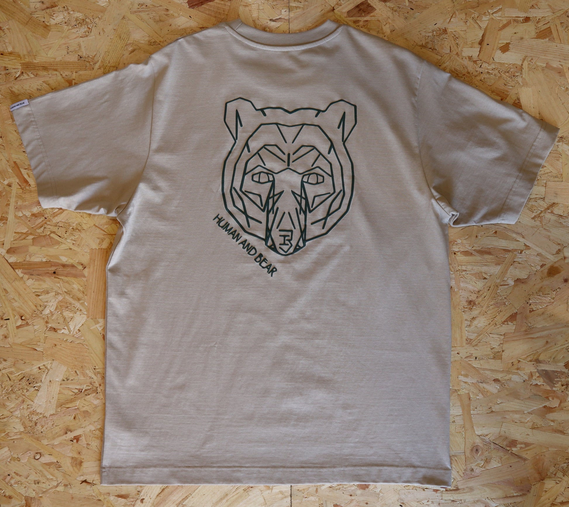 Beige t-shirt with bear graphic on a wooden surface