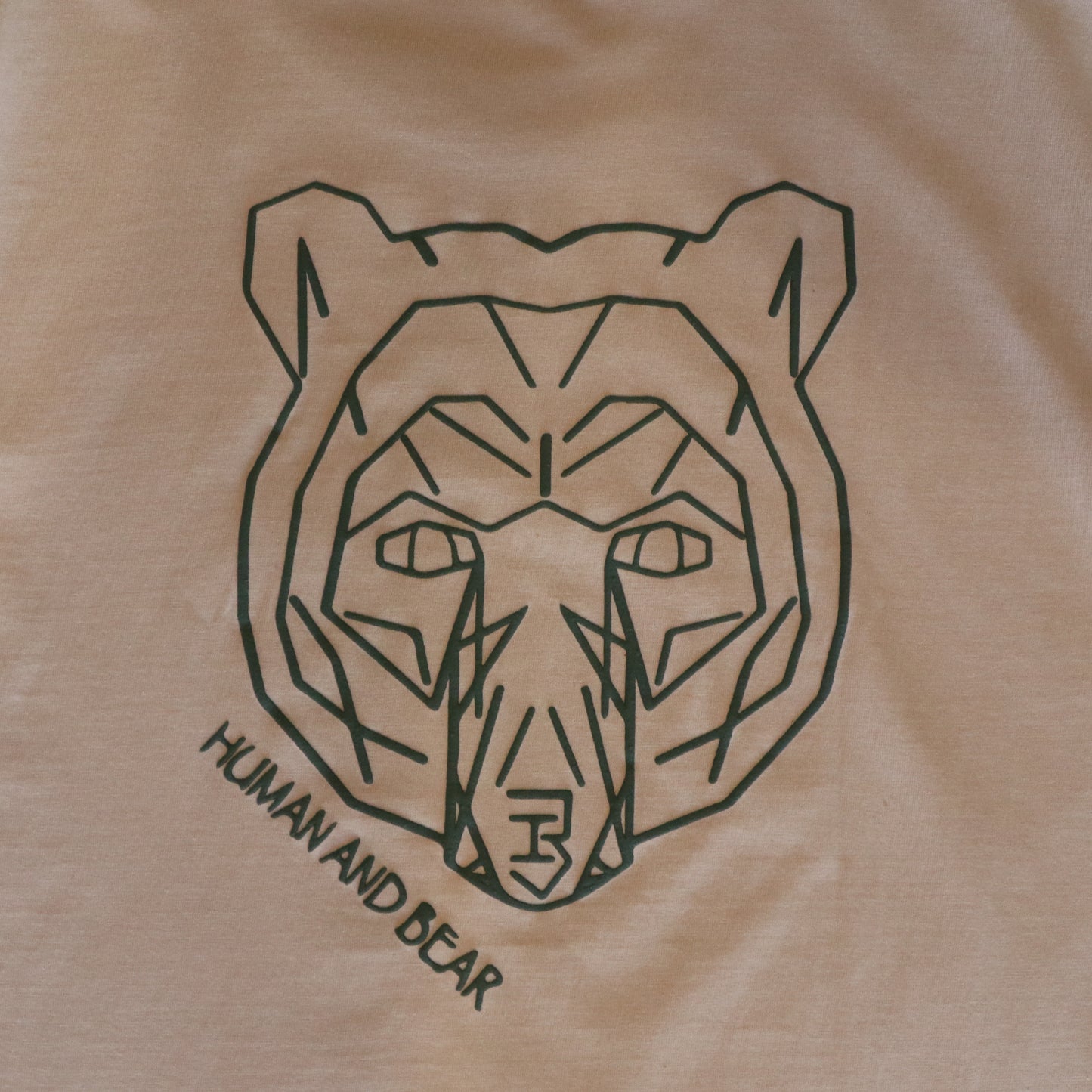 Beige t-shirt with a black geometric bear design and 'Human and Bear' text.