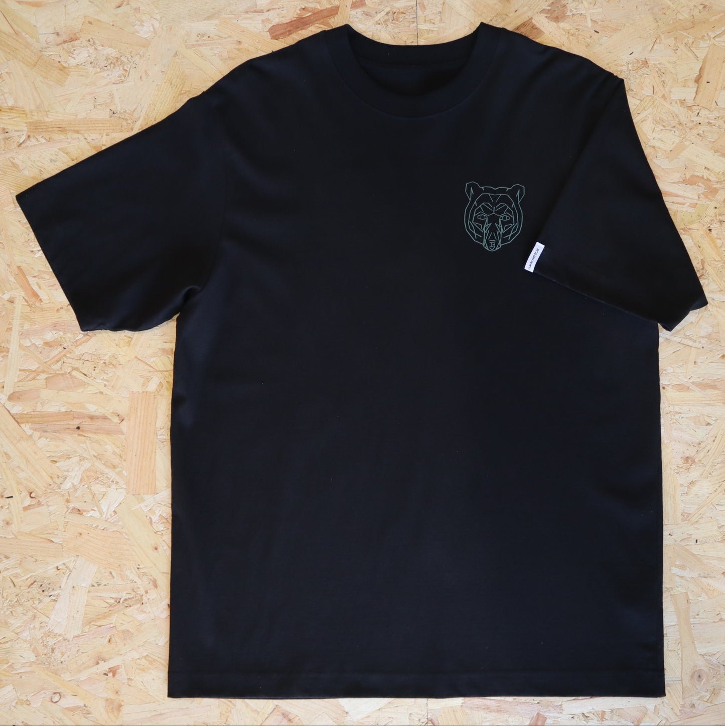 Black t-shirt with a bear logo on a wooden surface