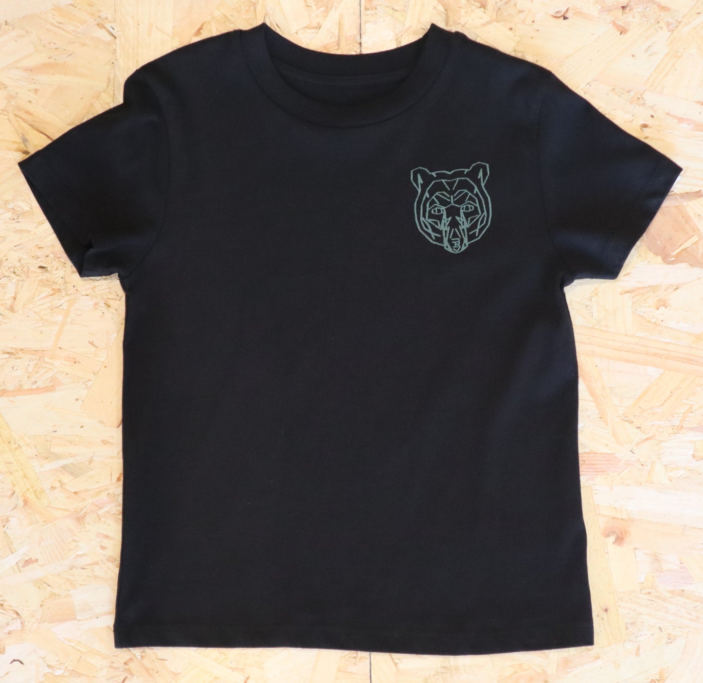 Black t-shirt with a green bear logo on a wooden surface