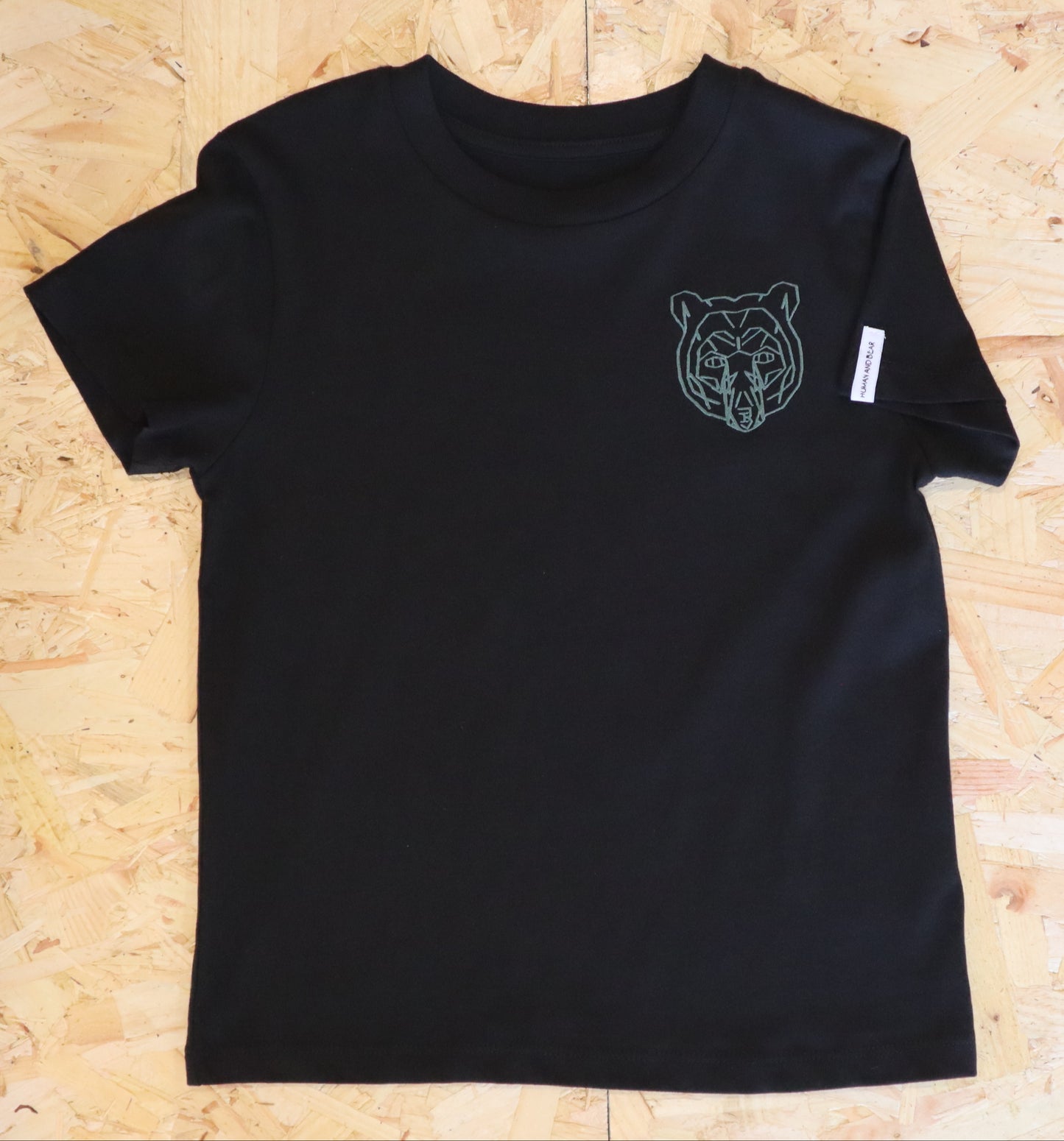 Black t-shirt with a bear graphic on a wooden surface