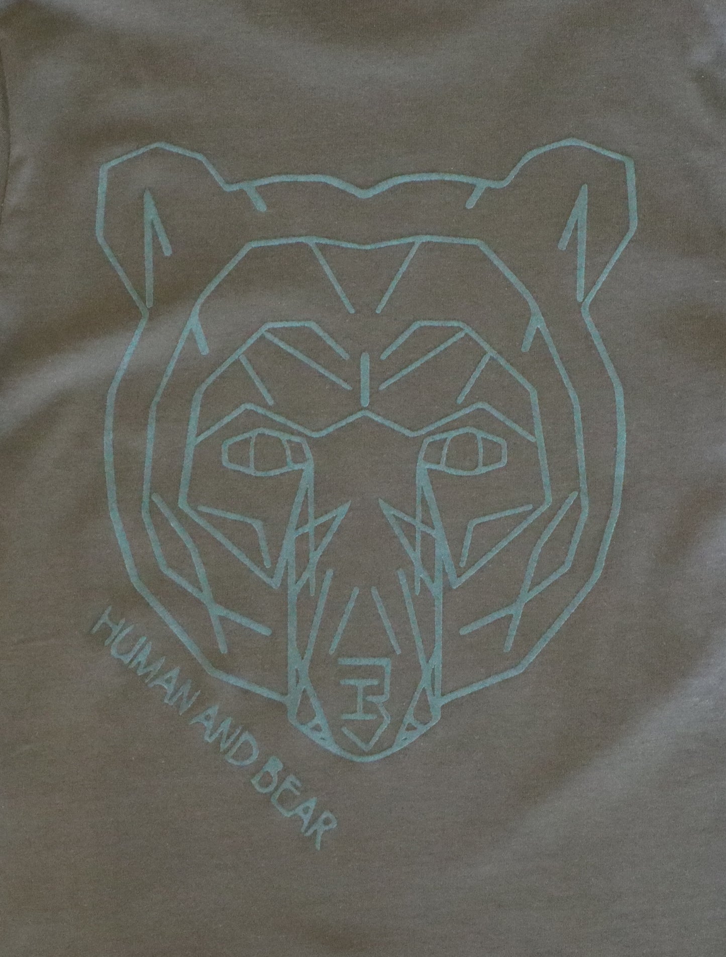 Khaki shirt with a green geometric bear design and 'Human and Bear' text.